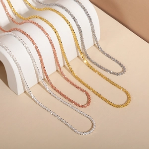 Detail of four glittering star necklaces in silver, gold, rose gold and dark grey metal