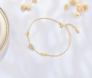 Detailed shot of golden sterling silver bracelet with pavé zircon cylinder charm on silk