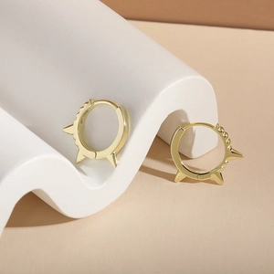 Macro detail of S925 sterling silver gold punk spike hoop earrings with sharp rivet design