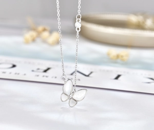 Vue macro d'un pendentif papillon en argent 925 avec nacre blanche et petit diamant brillant