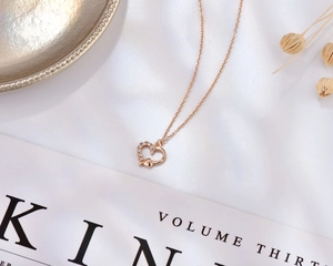 Close-up of rose gold heart necklace with zircon inlay on elegant white silk fabric