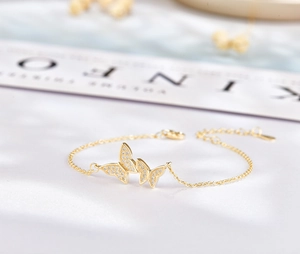 Vue macro du bracelet papillon doré orné de zircons blancs sur une chaîne délicate
