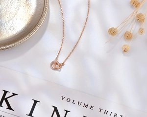 Dettaglio macro della collana geometrica in oro rosa con anello di cristallo su seta