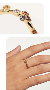 Vue macro et porté main d'une bague en argent doré sertie de zircons arc-en-ciel