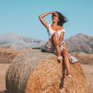 Outdoor shot of a model wearing a white off-shoulder crop top and floral maxi skirt