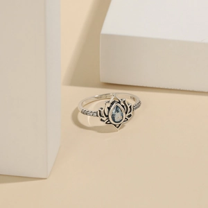 Macro detail of S925 silver lotus ring with pear-cut blue zircon and geometric decor