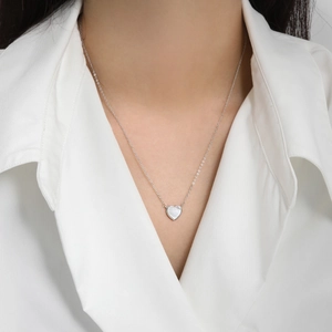 Collier coeur en argent s925 avec nacre blanche porté par un mannequin en chemise blanche