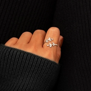 Macro shot of silver olive leaf open ring with zircon inlay worn on a hand