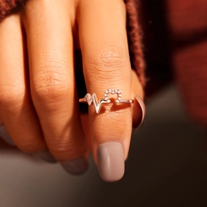 Close-up of rose gold heartbeat ring with heart-shaped zircon inlay on a model finger