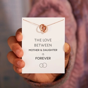 Close-up of interlocking rose gold rings with pavé crystals on a gift card backdrop