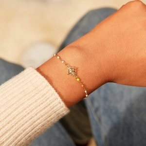 Elegante bracciale loto dorato con perline di smalto colorate al polso di una donna