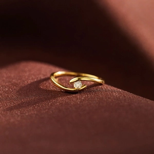 Macro shot of minimalist gold criss-cross ring featuring a single round zircon inlay