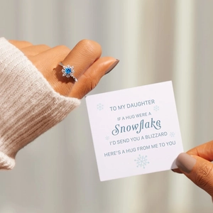 Detailed view of silver snowflake ring with blue gemstone and a message gift card