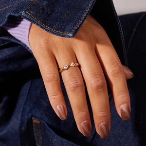 Close-up of golden open ring with double heart-shaped zircons worn by a female model