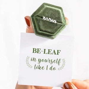 Gros plan d'une bague feuille en argent avec zircons et un coffret à bijoux en velours vert