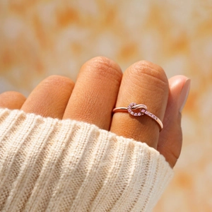 Elegant rose gold knot ring with pink paved gemstones worn on a model's hand