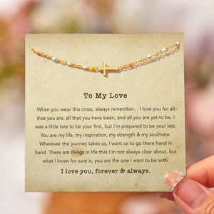 Détail du bracelet croix dorée avec perles colorées sur carte cadeau romantique