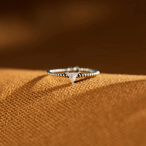 Macro shot of silver beaded ring featuring a clear triangle cut zircon stone setting