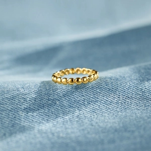 Vue macro d'une bague perlée dorée minimaliste montrant une texture ronde élégante