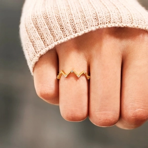 Elegant s925 silver zigzag ring in gold with sparkling diamonds on a knit sleeve background