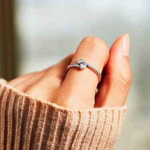 Close-up of double heart silver ring with pavé diamonds worn with a cozy sweater