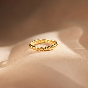Gros plan détaillé d'une bague en argent s925 perlé doré sur un fond en satin élégant