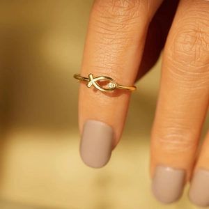 Vue macro détaillée d'une bague poisson dorée avec un œil en zircon brillant portée au doigt
