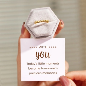 Détail d'une bague à bulles dorée dans un écrin en velours gris avec carte cadeau
