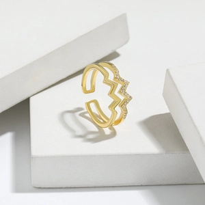 Macro detail of gold double-layered zigzag ring with cubic zirconia stones on white stone
