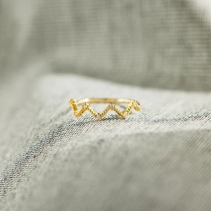 Macro shot of gold heartbeat ring with shimmering crystals on textured background