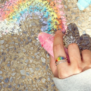 Detailed view of S925 silver rainbow gradient zircon rings on a creative colorful background