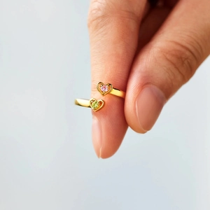 Detailed macro of gold-plated open ring with pink and lime green heart-shaped zircons