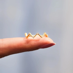 Macro shot of gold V-shaped wavy ring with shimmering small white gemstones set in metal