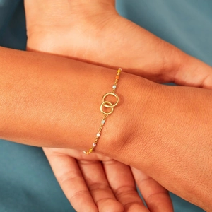 Detailed view of gold interlocking rings bracelet with colorful beads on wrist