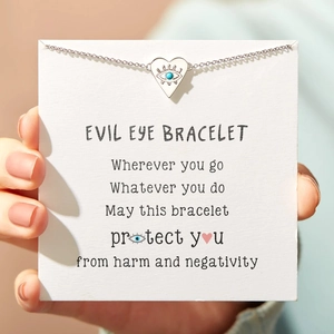 Detail of s925 silver evil eye heart bracelet held by hand with packaging card