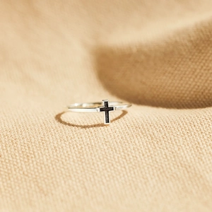 Gros plan sur une bague minimaliste en argent S925 avec détail de croix en émail noir