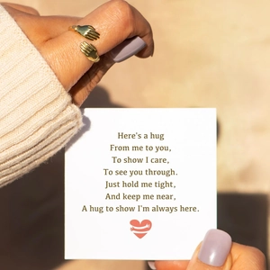 Minimalist gold hugging hands ring for women featuring a warm greeting card and gift box