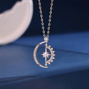 Macro shot of rose gold crescent moon and star pendant with sparkling zircon insets