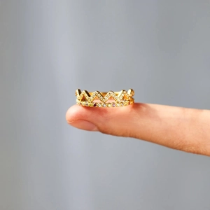 Gros plan d'une bague dorée à double couche avec vagues en zigzag et zircons colorés