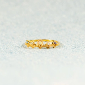 Bague couronne s925 dorée avec opale et pierres précieuses sur un tissu texturé bleu