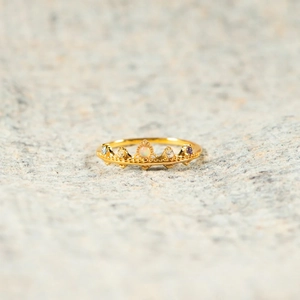 Bague couronne dorée élégante avec opale et pierres précieuses sur fond de pierre