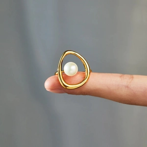 Close-up of modern s925 silver irregular gold ring featuring a white pearl on finger