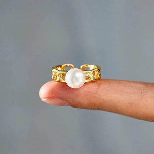 Close-up of a gold Cuban chain link ring featuring a white round pearl center on a finger