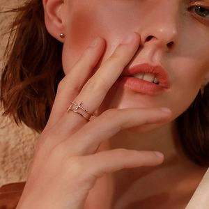 Detail shot of stacked S925 sterling silver cross ring and gold T-style band on model