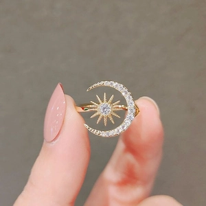 Macro shot of gold crescent moon and star zircon open ring held between fingertips