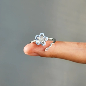 Macro shot of s925 silver ring featuring a blue enamel flower and zircon on fingertip