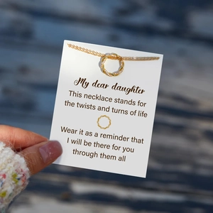 Detail of twisted gold knot pendant with zircon inlay on a sentimental gift card