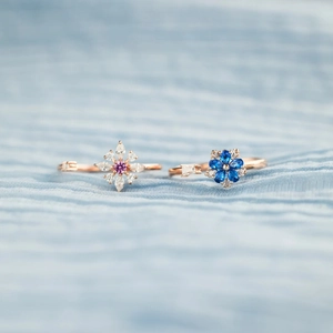 Elegant rotating blue flower and snowflake rings in rose gold with purple gemstones