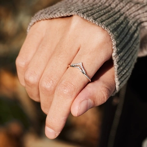 Gros plan d'une bague en argent en V double couche sertie de zircons au doigt
