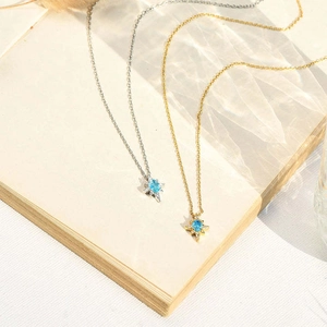Detail of starburst necklaces with blue zircon pendant in gold and silver finishes